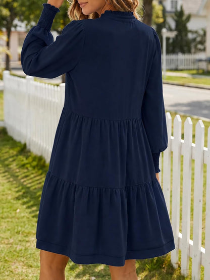 This charming dress features a flowy, tiered skirt and long blouson sleeves for a stylish, comfortable look that's perfect for any occasion.